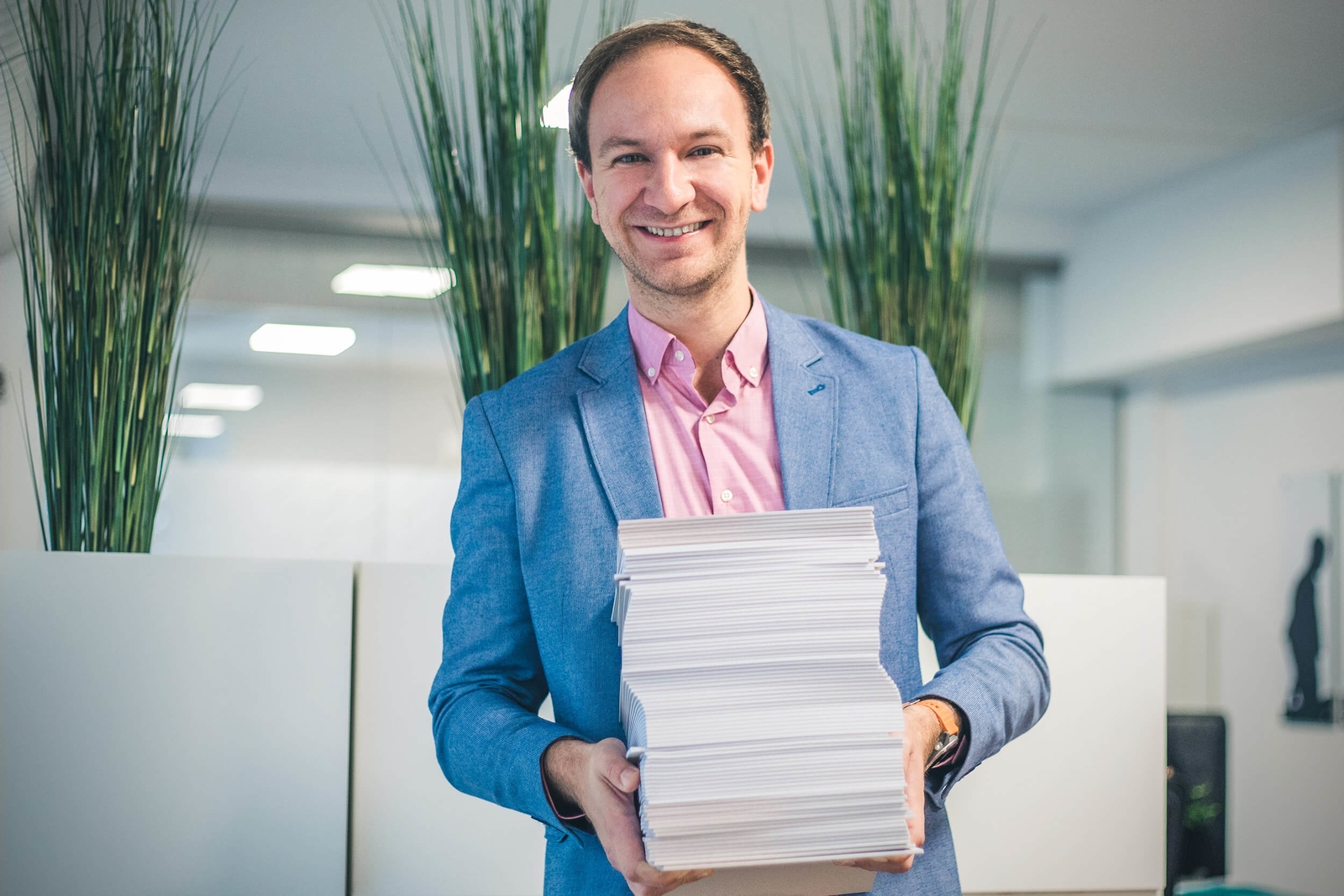 Florian Werner - Geschäftsführer der Agentur dreibein trägt einen Stapel Papier Blöcke