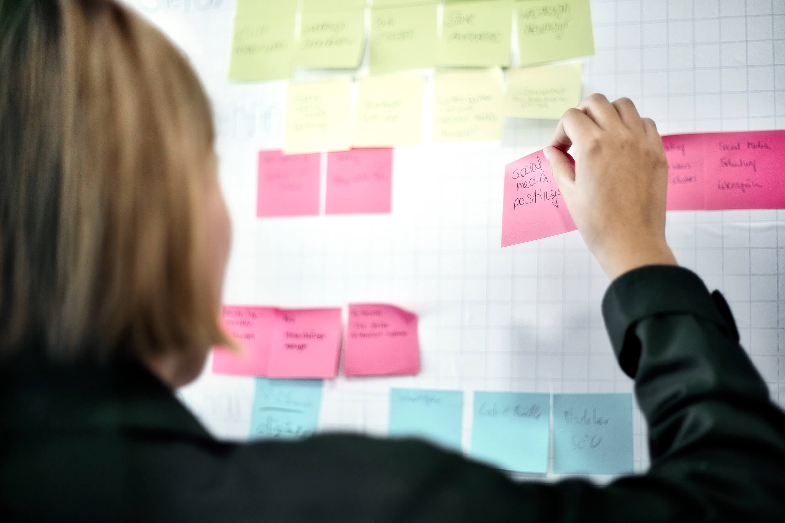 Mitarbeiterin plant Social Media Posts an einem Whiteboard